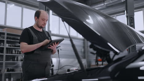 diagnostics of the car at the hood in the car service with a tablet. mechanic