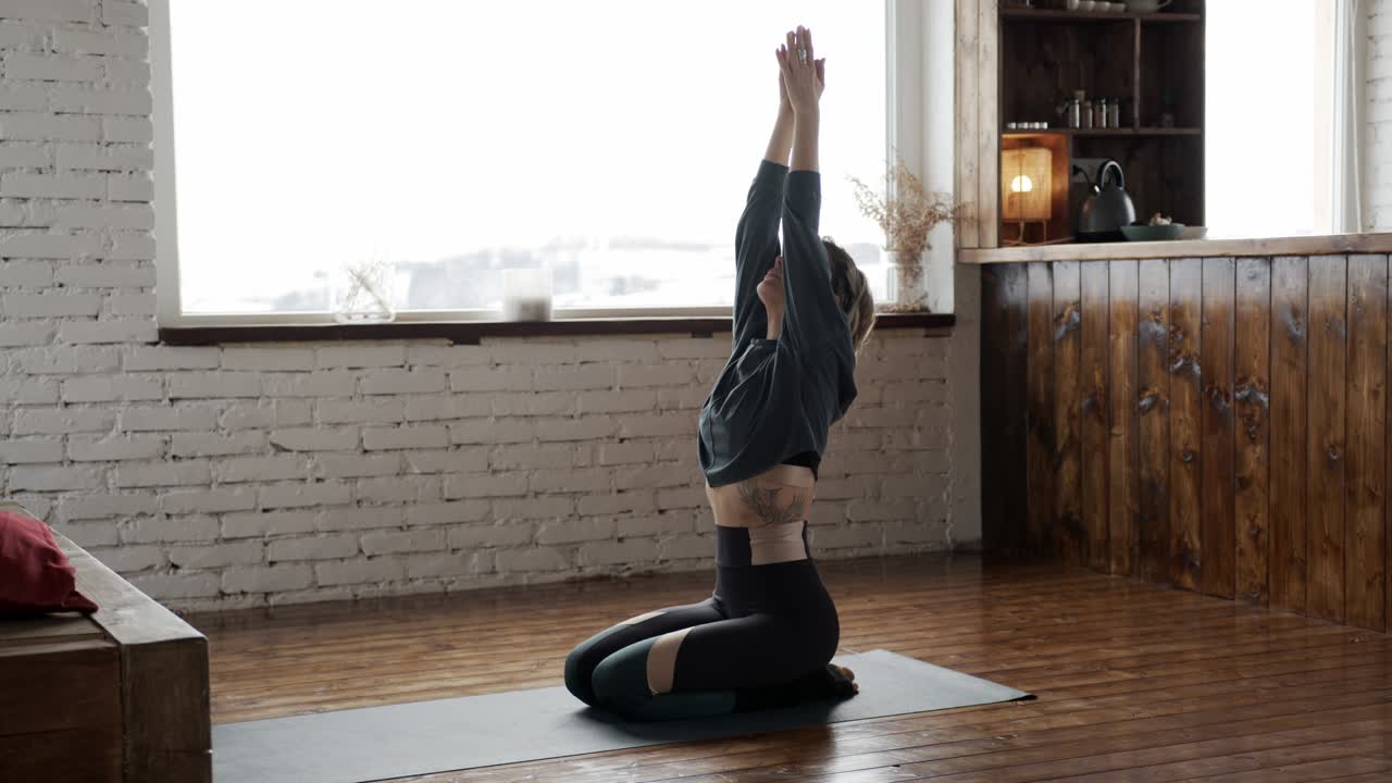 아름다운 젊은 백인 여성이 집에서 요가를 하고 있습니다.