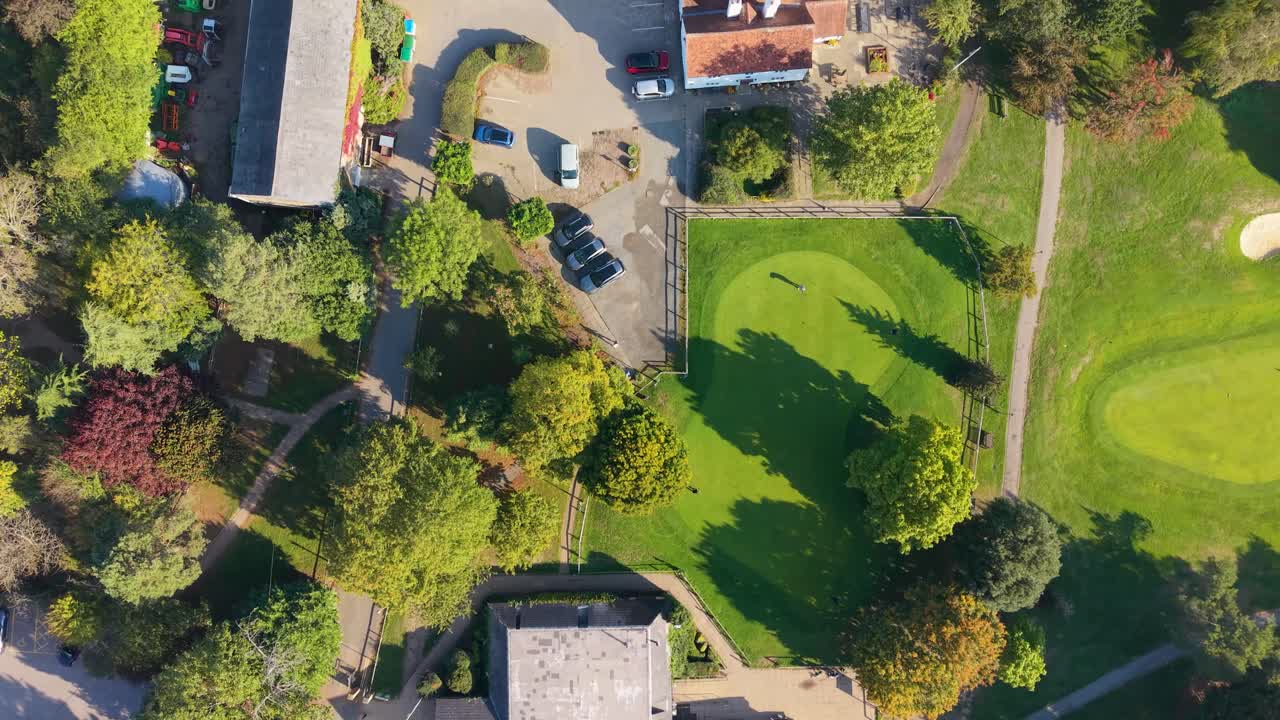 Top-down aerial drone shot of an 18-hole miniature golf course. The camera pans across fairways, bunkers, greens, rough and water hazards, showcasing a playful landscape for leisure and recreation