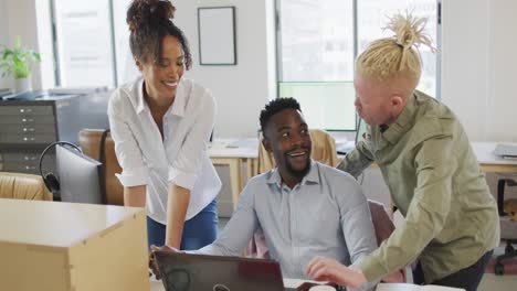 happy diverse business people discussing with laptop in creative office