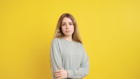 serious young woman crossing arms on yellow background