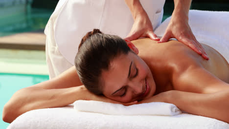 Happy-brunette-enjoying-a-massage-poolside