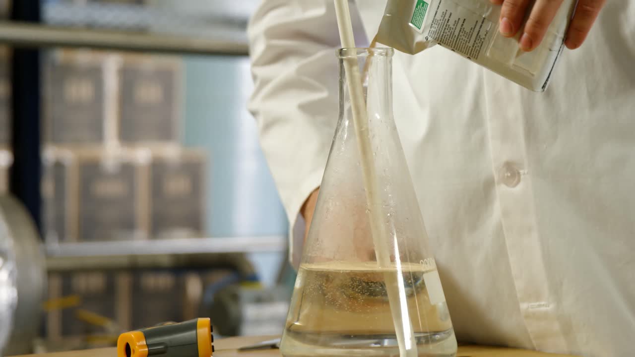 Male worker pouring liquor in flask 4k