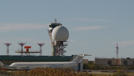 airplane taking off from airport with control tower and radar in view