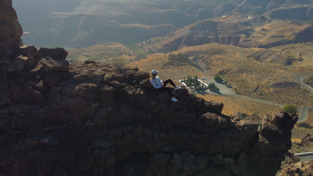 Aerial view revealing a woman on top of a rock formation on the island of Gran Canaria