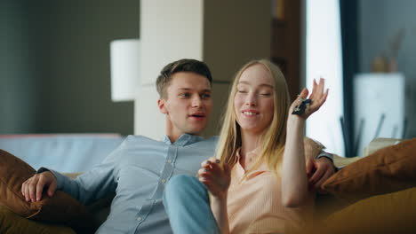 Couple-holding-keys-new-house-sitting-on-couch-close-up.-Family-rejoicing-home.