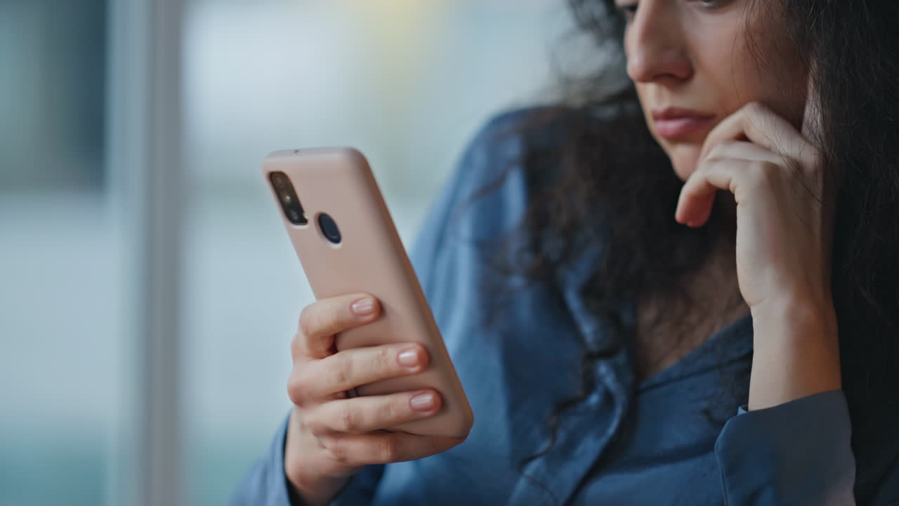 Serious employee looking smartphone in office. Closeup hand holding smart device