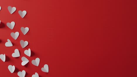 corazones de papel rosa sobre fondo rojo en el día de san valentín