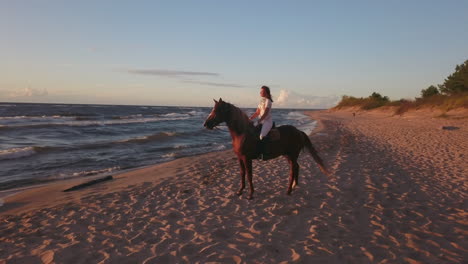 Girl-in-white-on-horse-sitting-on-a-beach,-4k