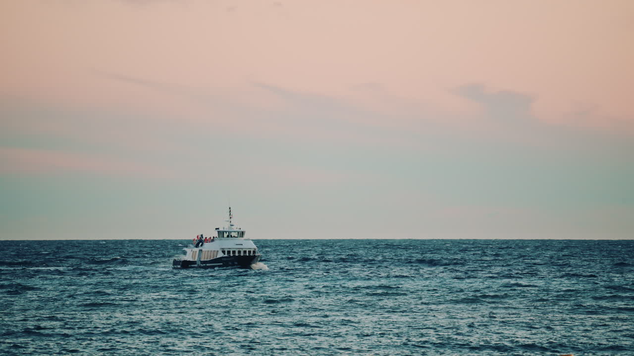 A ferry boat traveling across open water under a pastel sky