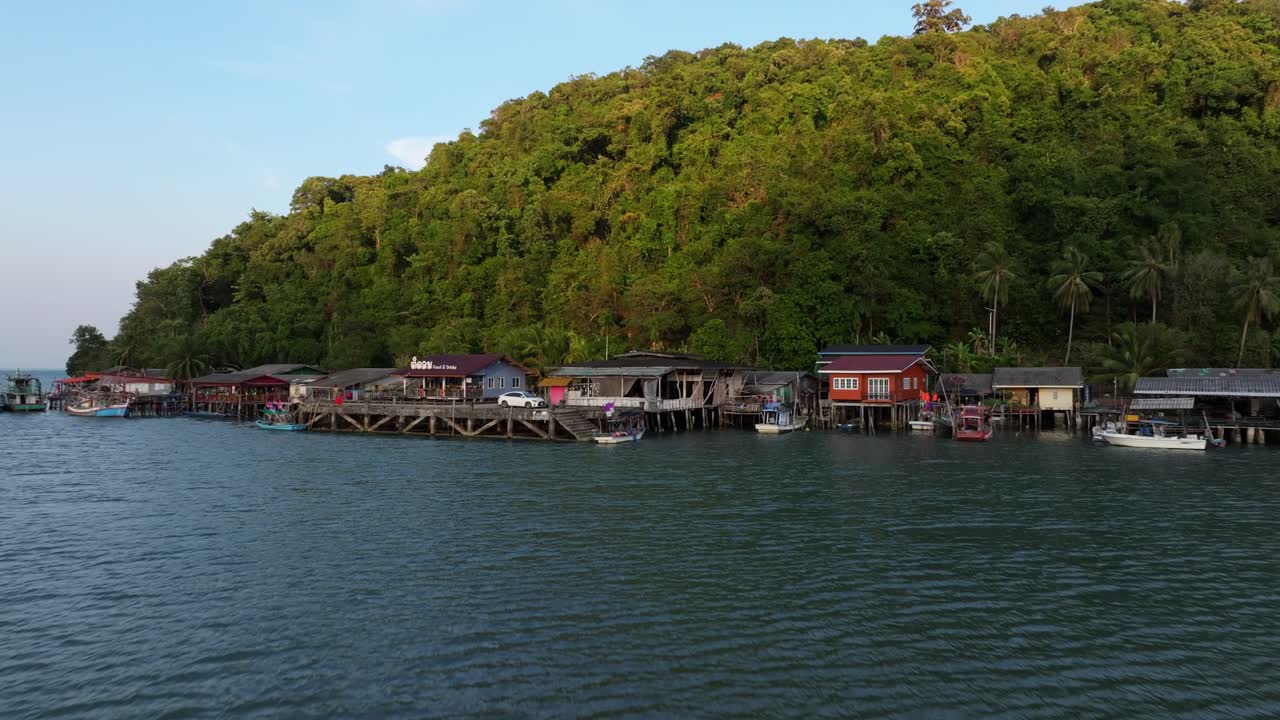 Tayland, Koh Chang'da, altın saat ışığıyla yıkanmış kıyıdaki bir Tayland köyünün kuşbakışı görüntüsü.