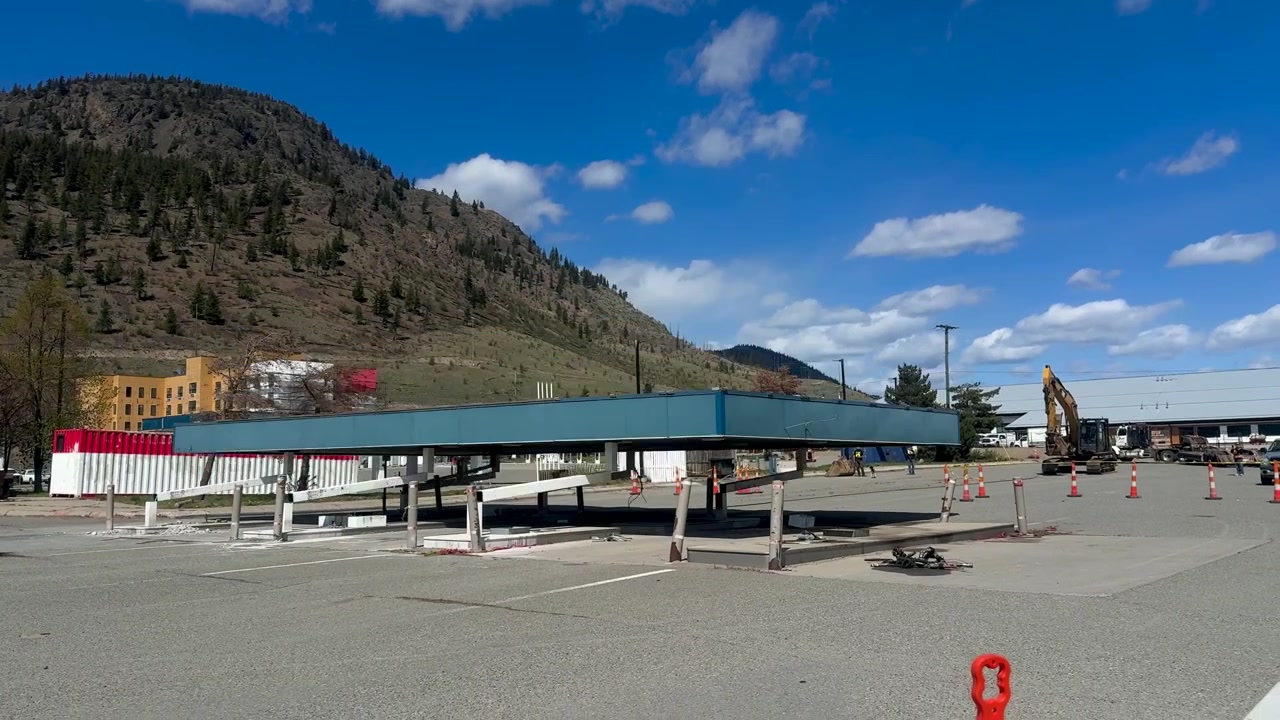 Ripresa statica di una stazione di servizio in costruzione con una pensilina riflettente e attrezzature sullo sfondo di una montagna a Merritt, Columbia Britannica