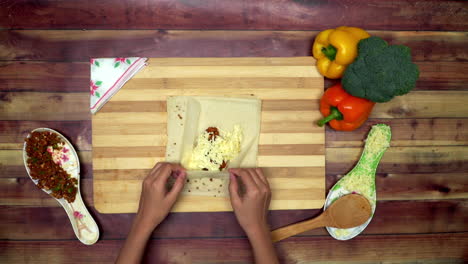 a top view of covering the rolls having inside cheese and marinated mince, two big yellow and red capsicums and a green broccoli on the table