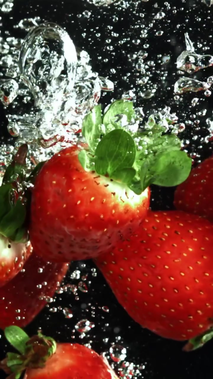 Fragole rosse fresche che schizzano nell'acqua al rallentatore