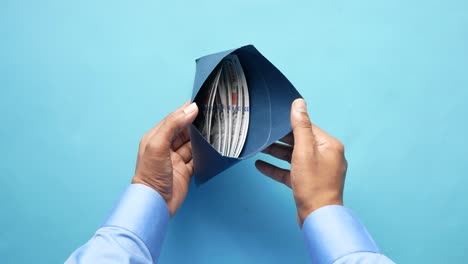 persona abriendo un sobre azul con dinero