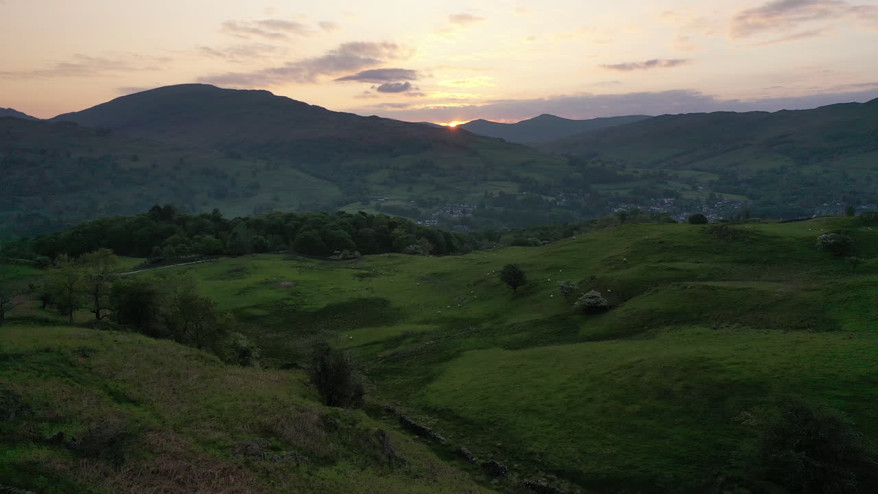 Ripresa aerea che si alza lentamente da Loughrigg Fell all'alba con vista su Ambleside