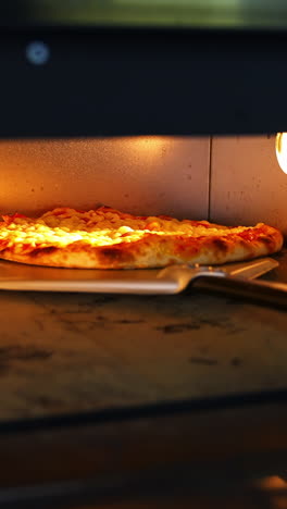 pizza in oven. baking pizza. the chef is turning hot pizza with a spatula in a stove. process of cooking pizza in pizzeria. tasty cookery. vertical video