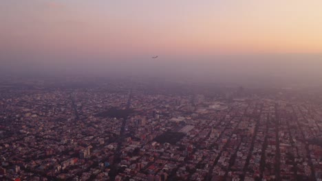 beautiful aerial footage of commercial airplane landing at golden hour in mexico city, smog glowing in the evening light
