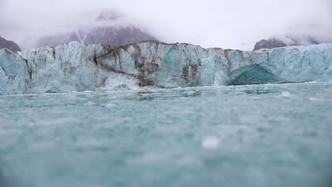 Pieces-of-Broken-Ice-Under-Glacier,-Low-Angle-View-From-Moving-Boat