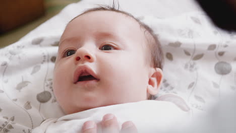 close up of loving father playing with newborn baby son lying on bed at home in loft apartment