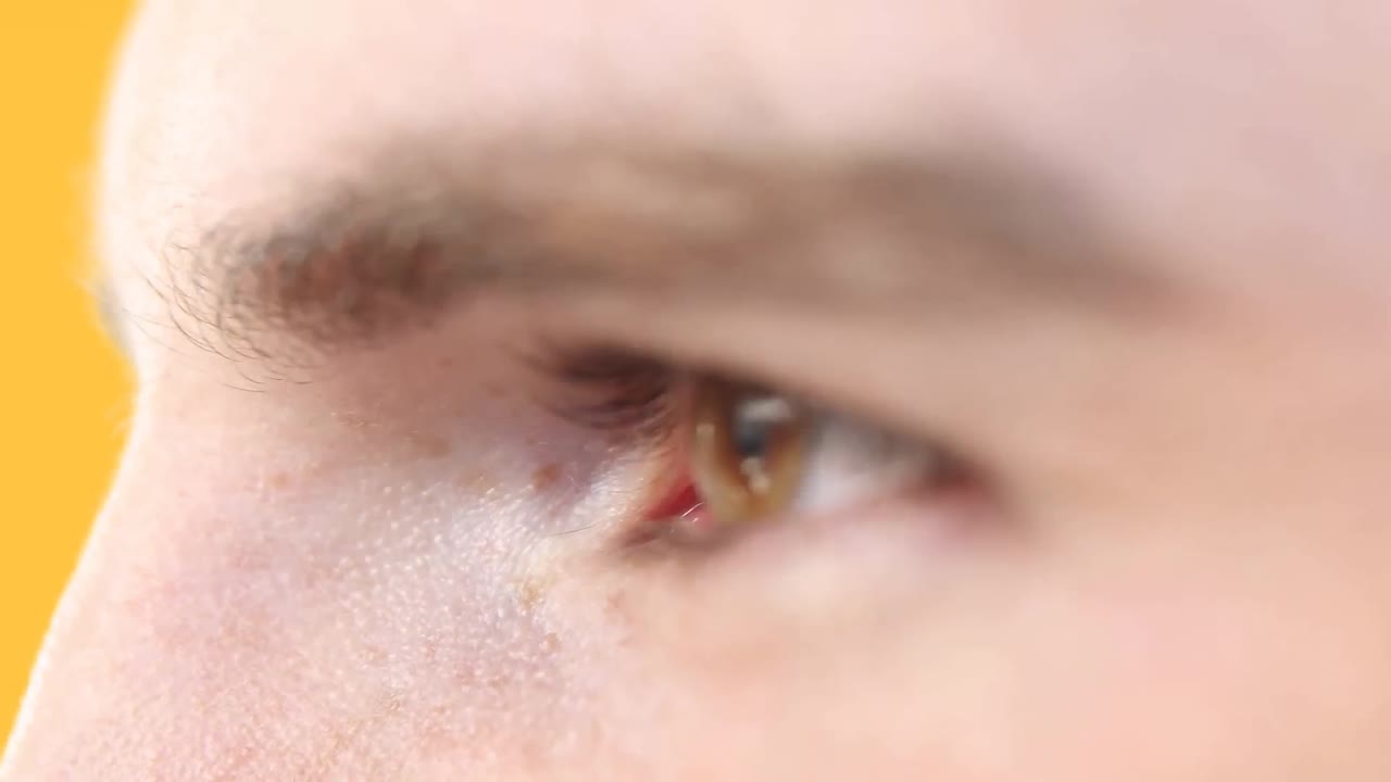 노란색 배경 에 백인 남자 의 눈 을 가까이 쳐다보는 장면