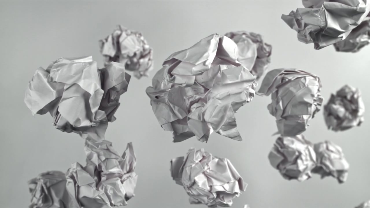 Palline di carta bianche accartocciate che fluttuano su uno sfondo grigio
