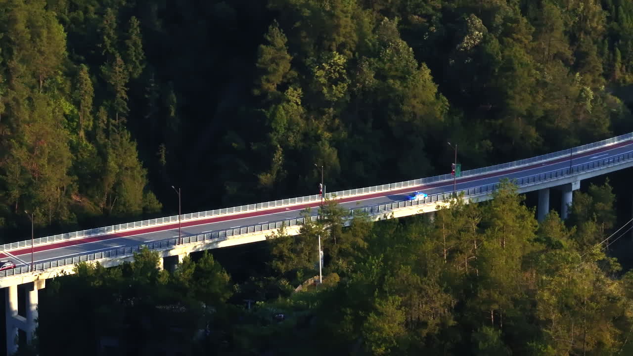 Aerial view following a taxi on bridge, between mountains in China, golden hour