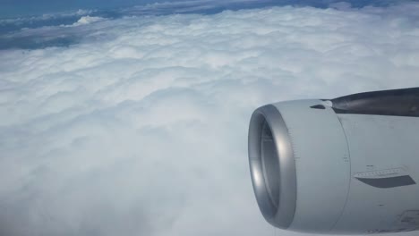 airplane wing and engine soaring above a sea of fluffy white clouds