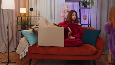 two girls playing in a cardboard box on the couch