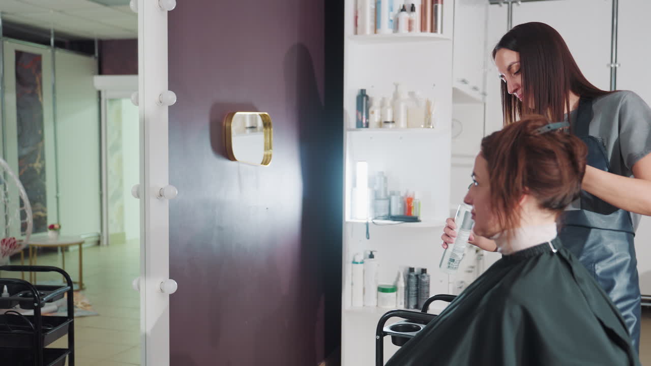 Tocco finale all'acconciatura: lo stilista applica lo spray di finitura, il parrucchiere completa lo styling con lo spray di finitura, lo stilista professionista completa con sicurezza i ritocchi finali con i prodotti di finitura