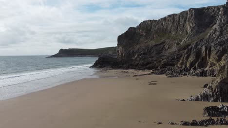 Luftdrohnenaufnahme-Des-Sandigen-Mewslade-Strandes-Mit-Ungewöhnlichen-Küstenfelsen-Und-Ruhigen-Meereswellen-Wales-Uk-4k