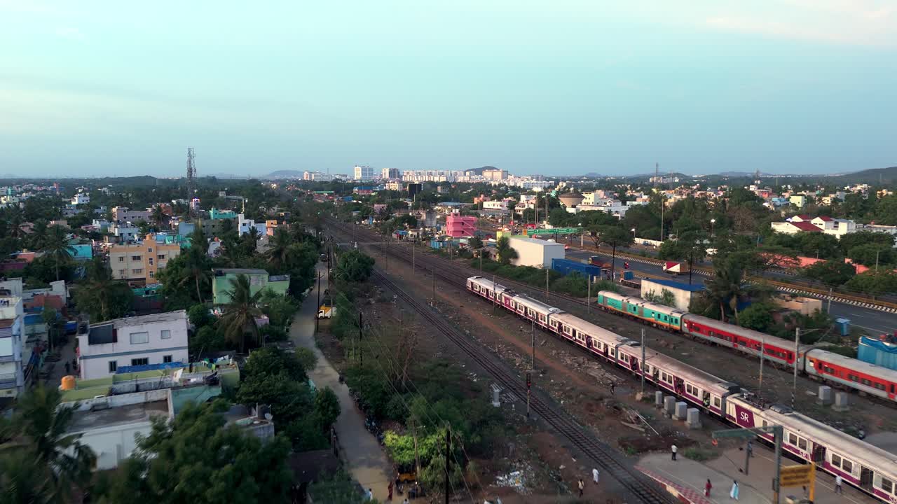 Aerial follow up shot of local train passing between cities during daytime.