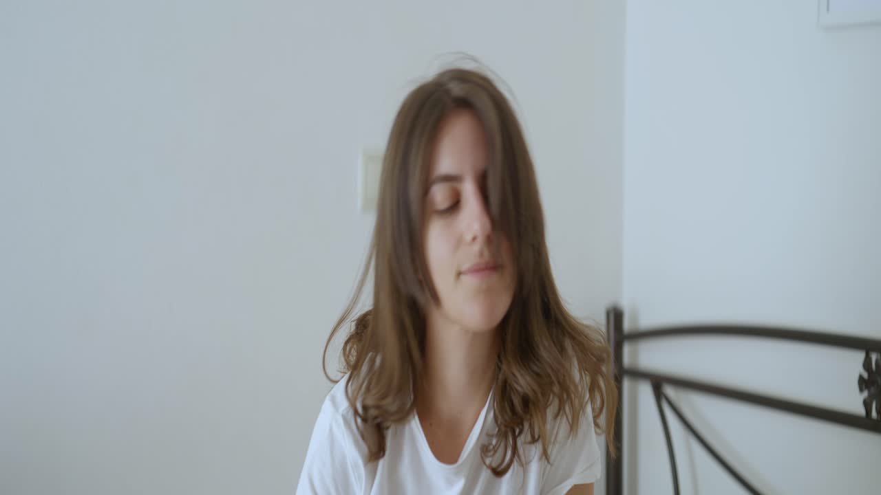 fotografía de cerca de una mujer de unos veinte años despertando y sentada en su cama