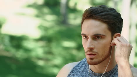 sport man using headphones for listening music on morning run in park