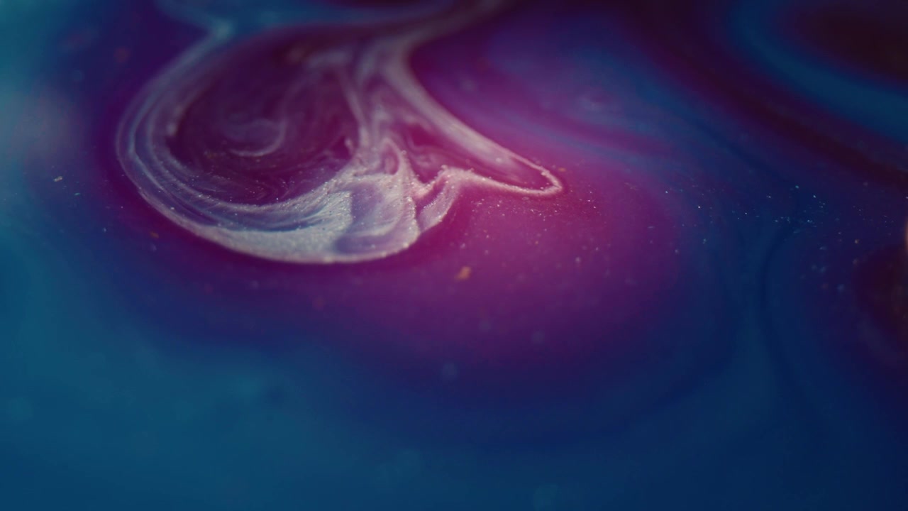 Scatto macro dall'alto di colori a inchiostro alcolico che si fondono in un vortice cinematografico di rosa e blu, che rappresenta un'evoluzione emotiva nel tempo in uno scatto packshot in studio