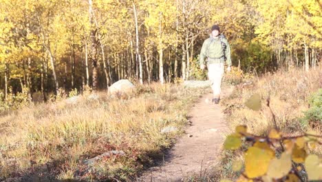 backpacker walking towards the camera with fall aspen leaves in the background