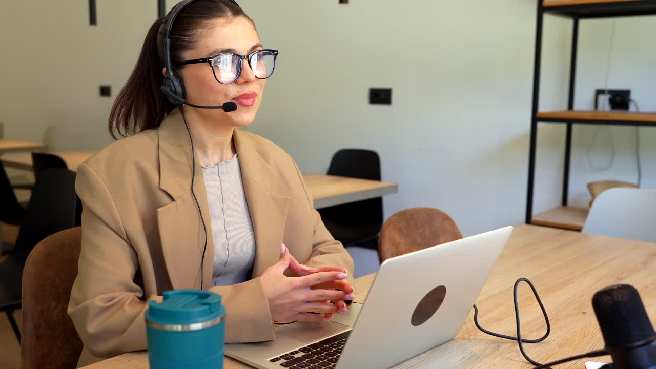Woman in headset working on laptop in office