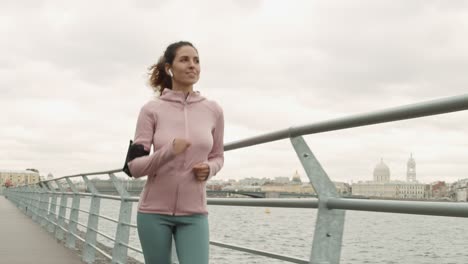 cheerful athletic woman running along embankment