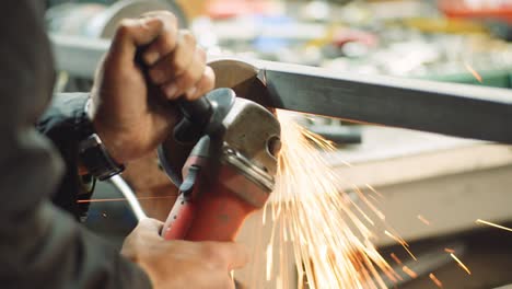 steel industry - man using angle grinder grinding metal object at workshop.