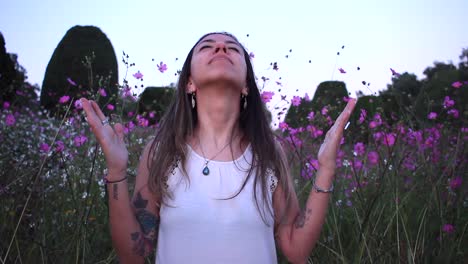 joven latina agradecida con dios en medio de un hermoso campo morado con flores de hojalata
