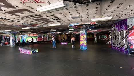 un patinador realizando trucos en un parque de patinaje cubierto de graffiti