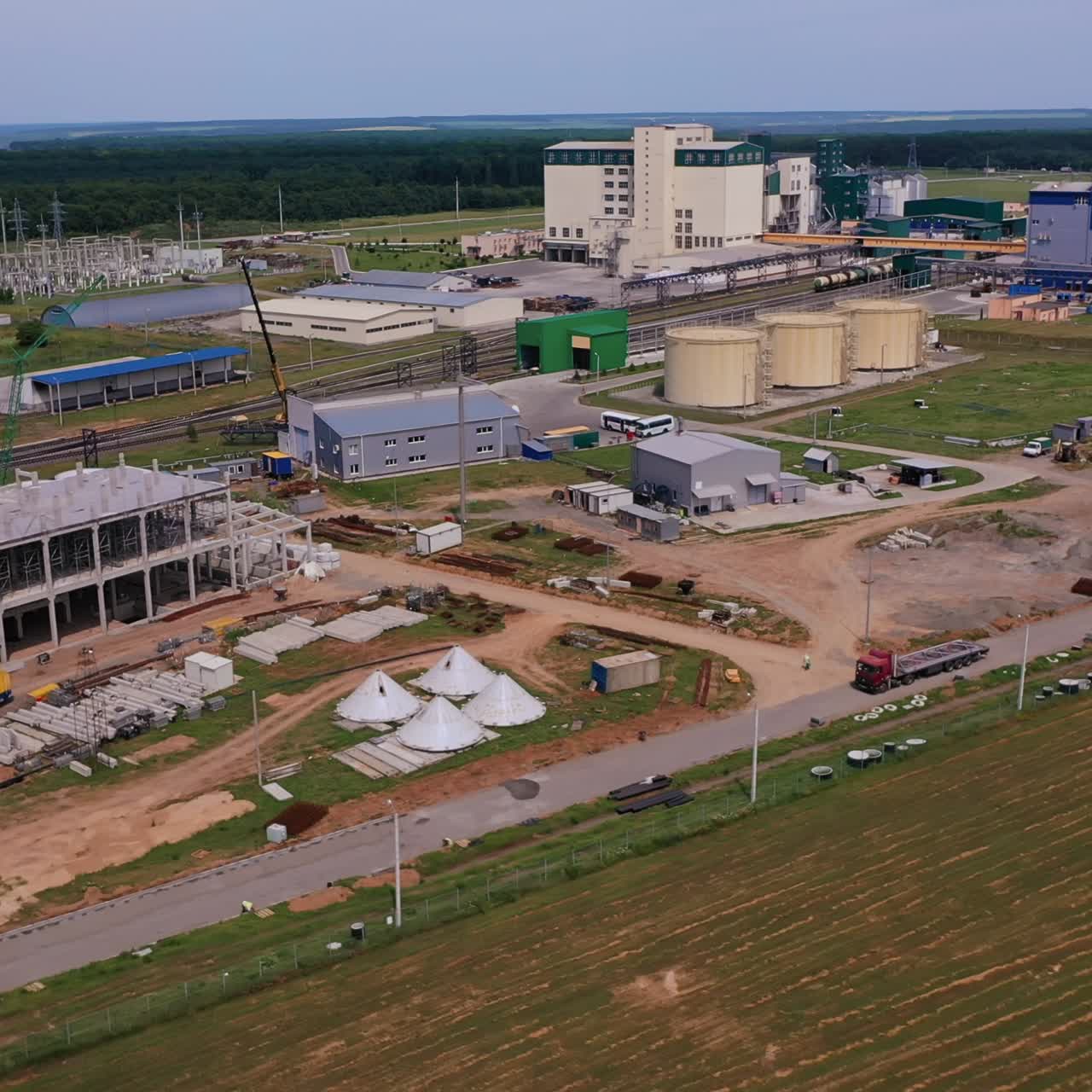 Huge plant for processing harvest. Modern working plant alongside the new premises under construction. Beautiful nature at the backdrop