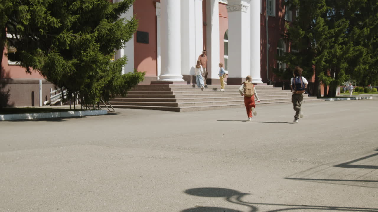Children running out of a school building with backpacks