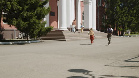 children running out of a school building with backpacks