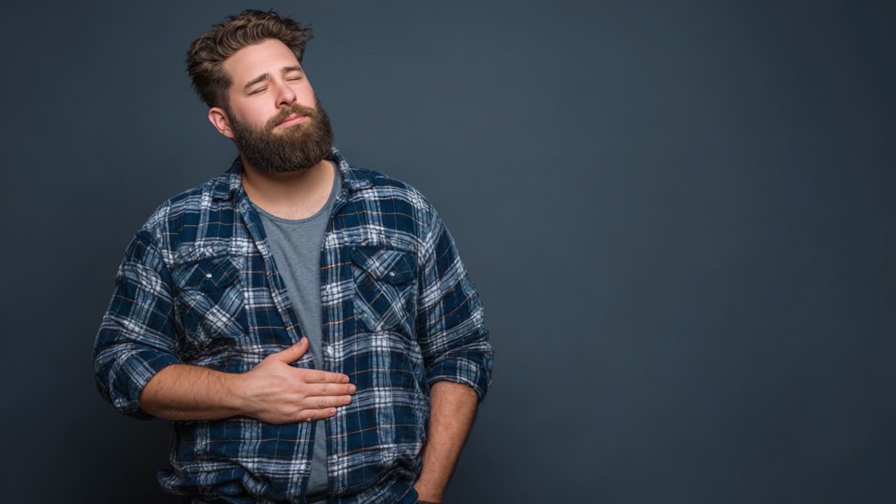 Un hombre que expresa malestar mientras se sujeta el estómago, retratando un momento de contemplación o angustia, ambientado sobre un fondo neutro que realza el tono emocional de la escena.