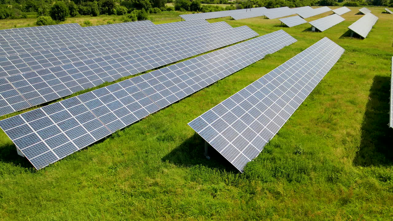 низкоскоростная аэрофотосъемка фермы солнечных батарей с солнечными лучами на зеленом поле крупным планом