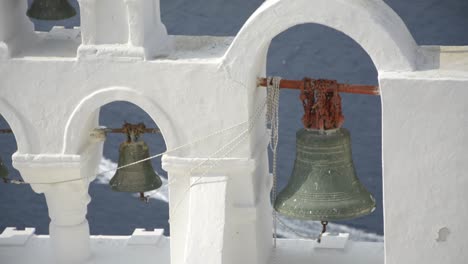 iconic church bells in oia, santorini, greece as a boat passes by