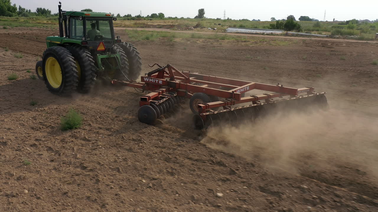 agricultor arando y cultivando un campo de maíz con un tractor como agricultura en el paisaje rural de colorado desde un dron aéreo