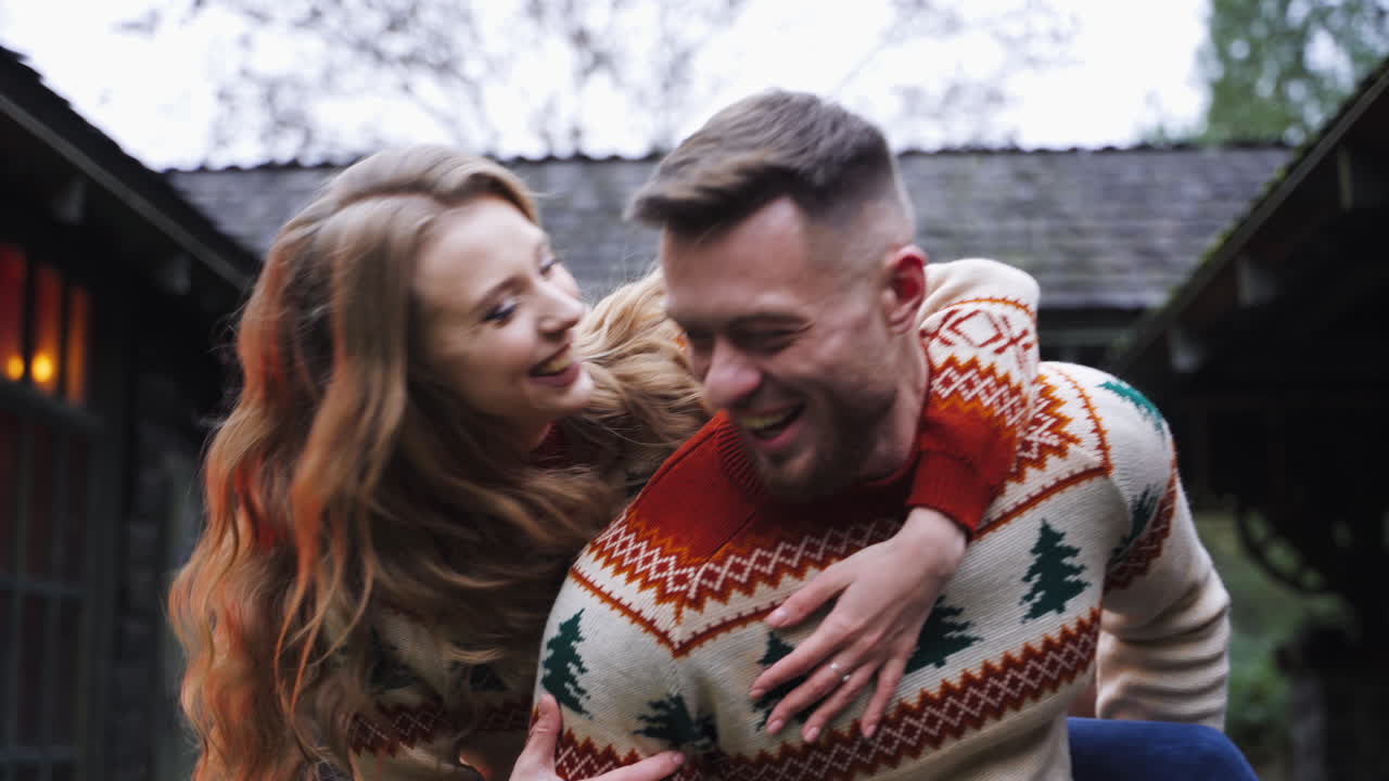 Happy couple having fun. Romantic couple in warm sweaters enjoying time together outdoors. Smiling girl on her boyfriends back. Close-up.