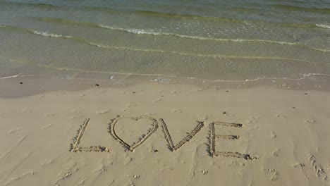 static shot of love inscribed in the sand on a beach